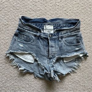 Light wash denim shorts with exposed pockets and raw hem, mid waist